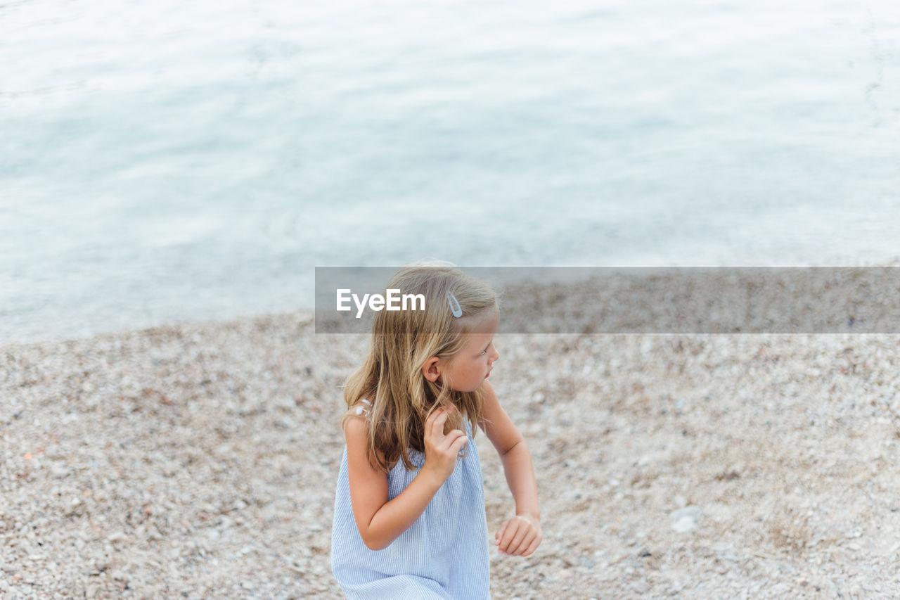 High angle view of cute girl looking away while standing at beach