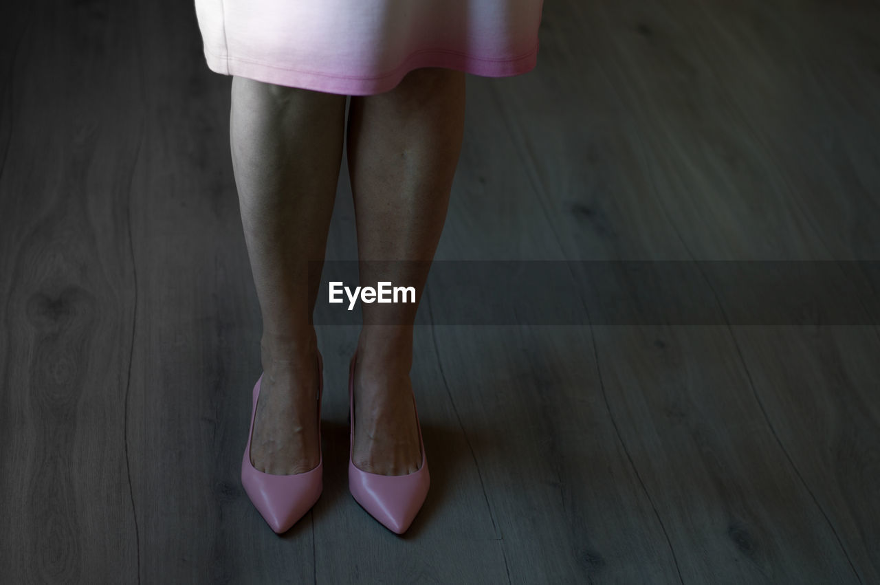 low section of woman standing on hardwood floor at home