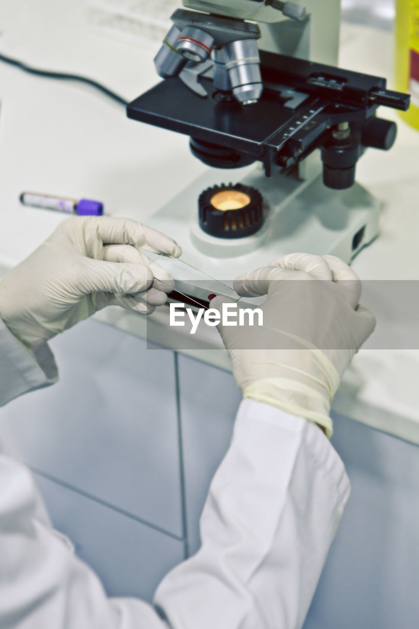 Midsection of scientist examining chemical at laboratory