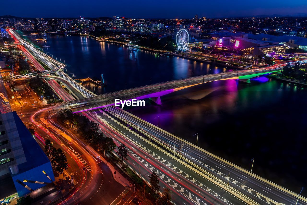 Aerial view of illuminated light trails on bridge in city at night