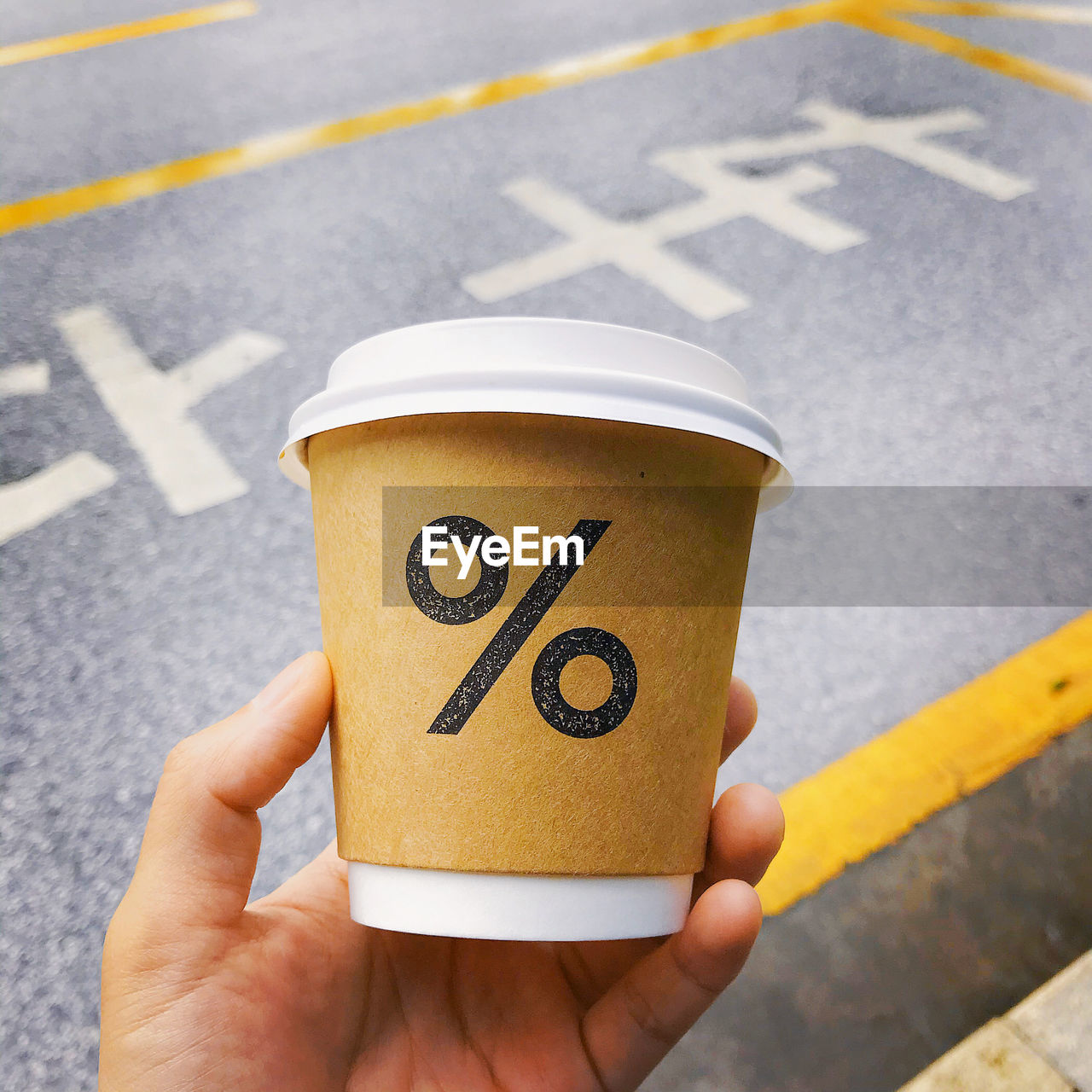 yellow, hand, symbol, holding, one person, road, city, street, transportation, sign, road marking, number, day, cup, high angle view, close-up, communication, adult, marking, outdoors, food and drink