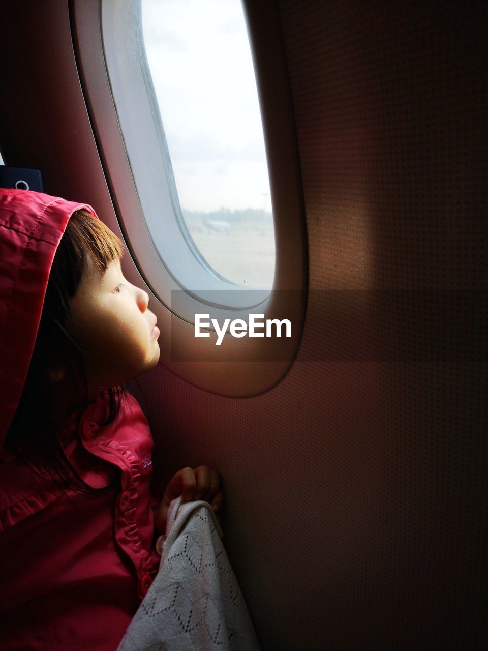 Girl looking away through airplane window