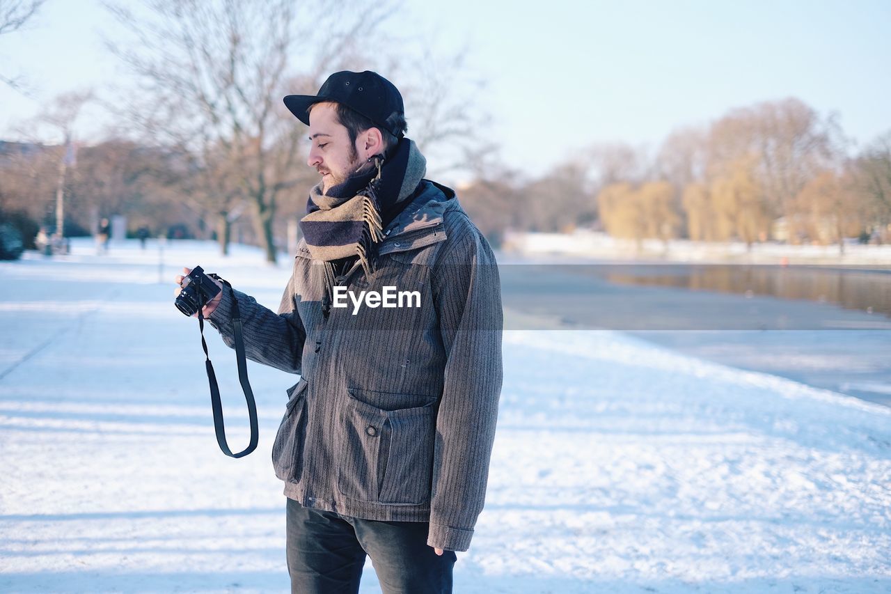 Man holding camera on street in snow