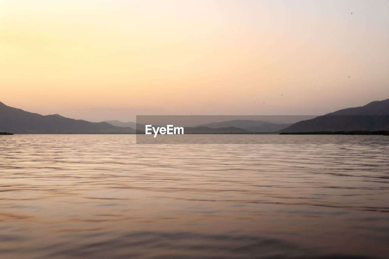 Beautiful sunset over calm warm lake with mountain in background