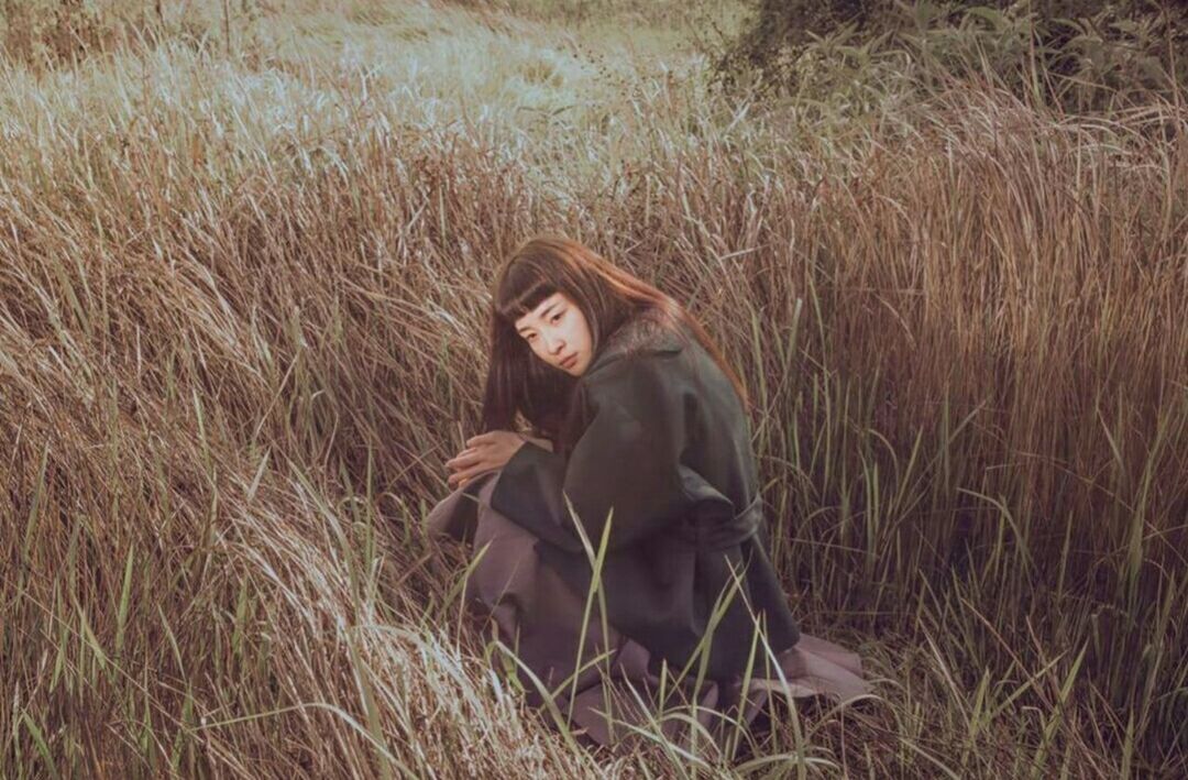 YOUNG WOMAN SITTING ON GRASS