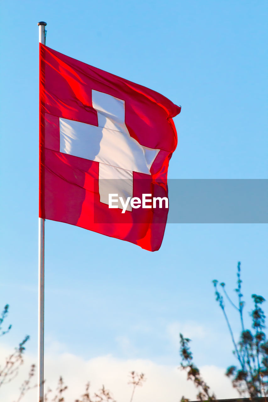 Switzerland national flag waving on blue sky background. swiss confederation, ch