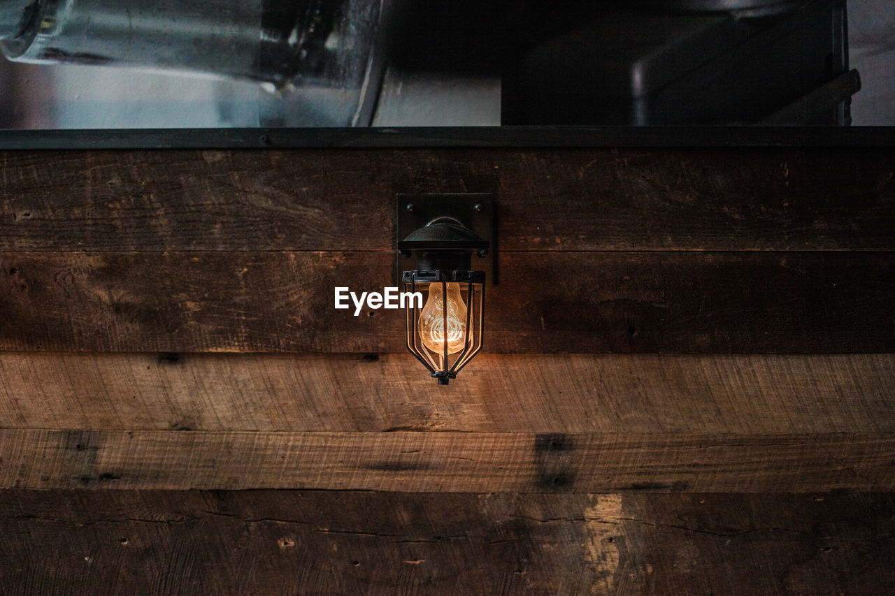 View of illuminated lighting equipment on wooden wall