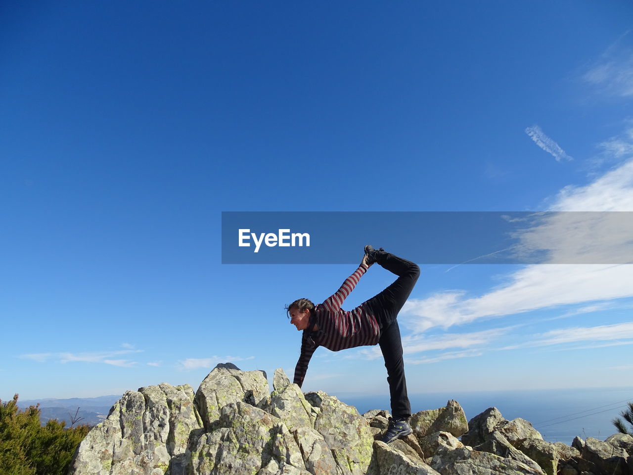 PERSON STANDING ON ROCK AGAINST SKY