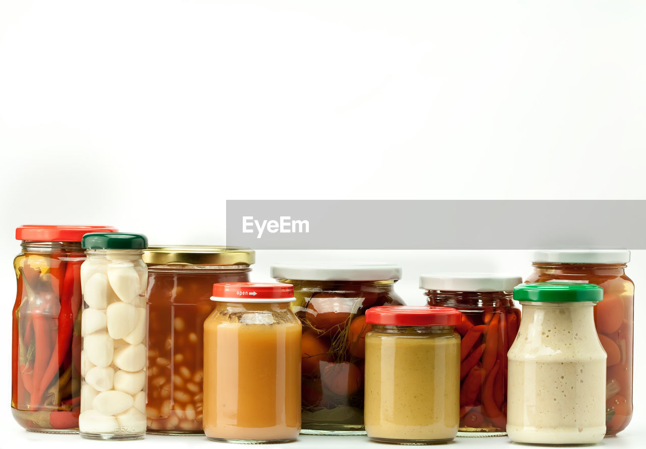 Close-up of various food in jars against white background