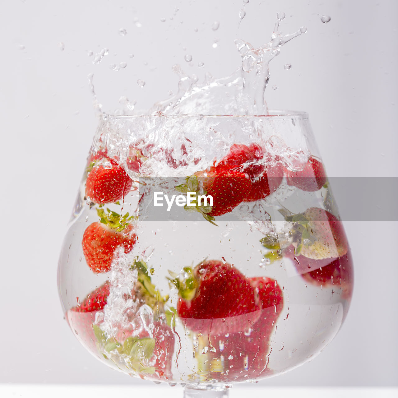 Close-up of strawberries in drinking glass against white background