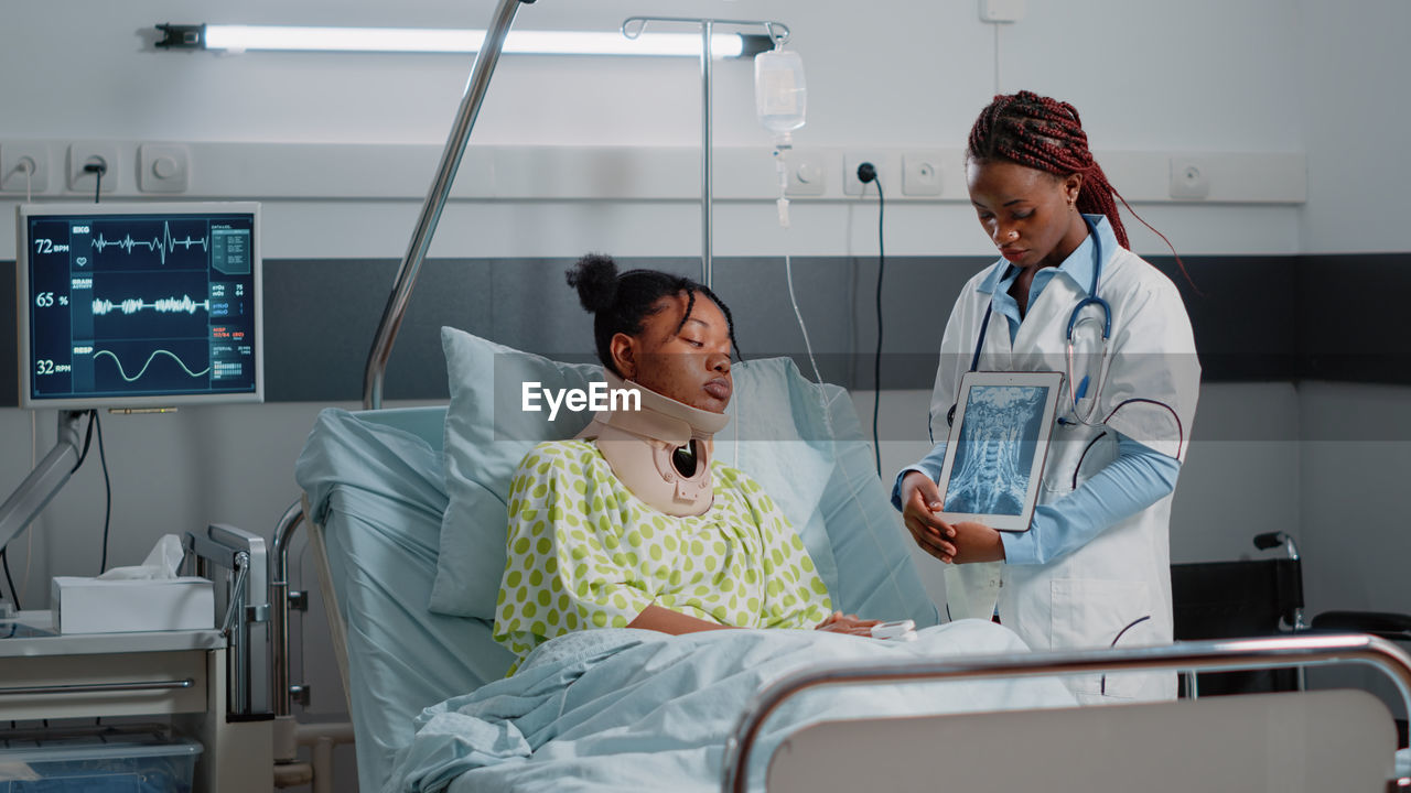 Doctor showing test result on tablet pc to patient in ward at hospital