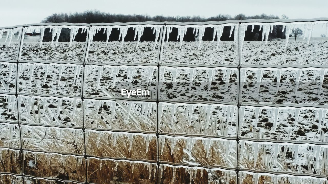 Frozen fence on snowcapped field during winter