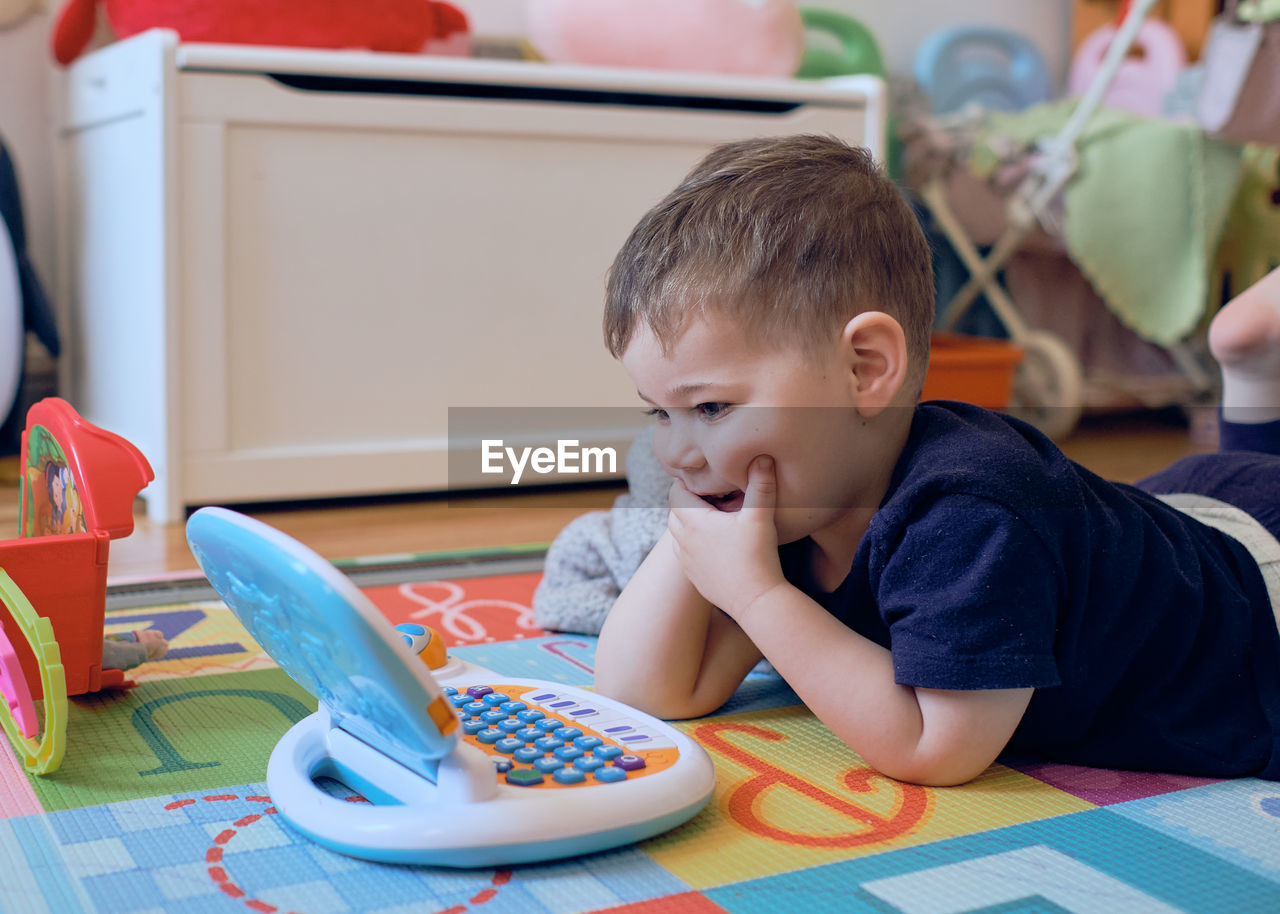 Curious little toddler playing with his toy computer