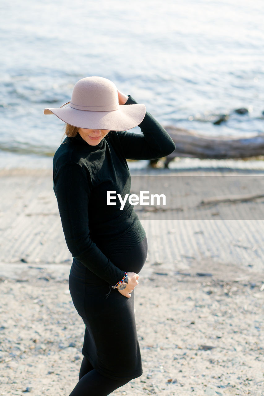 Portrait of a beautiful young pregnant woman in a black turtleneck and black tight skirt