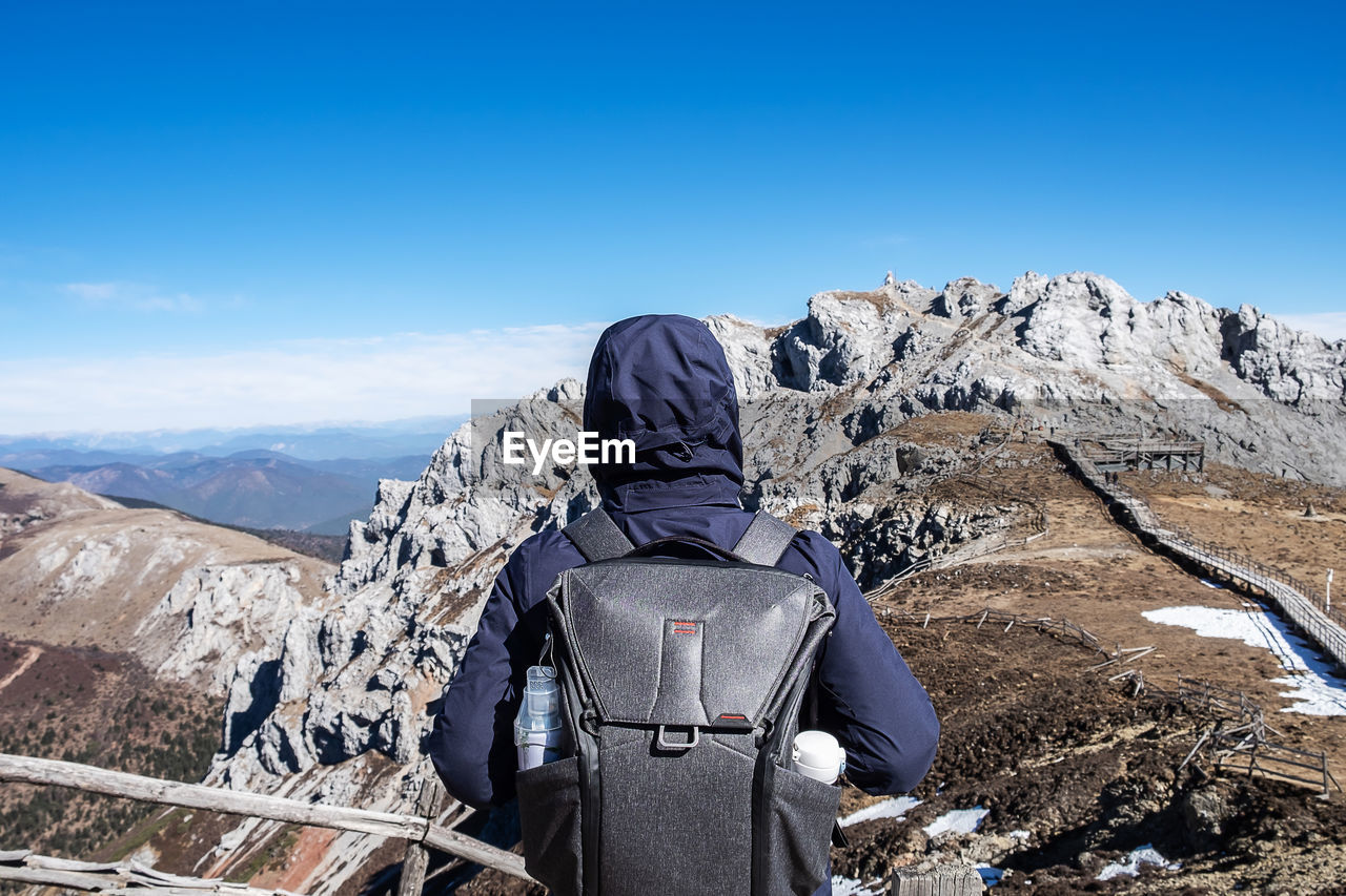 REAR VIEW OF PERSON ON SNOWCAPPED MOUNTAIN