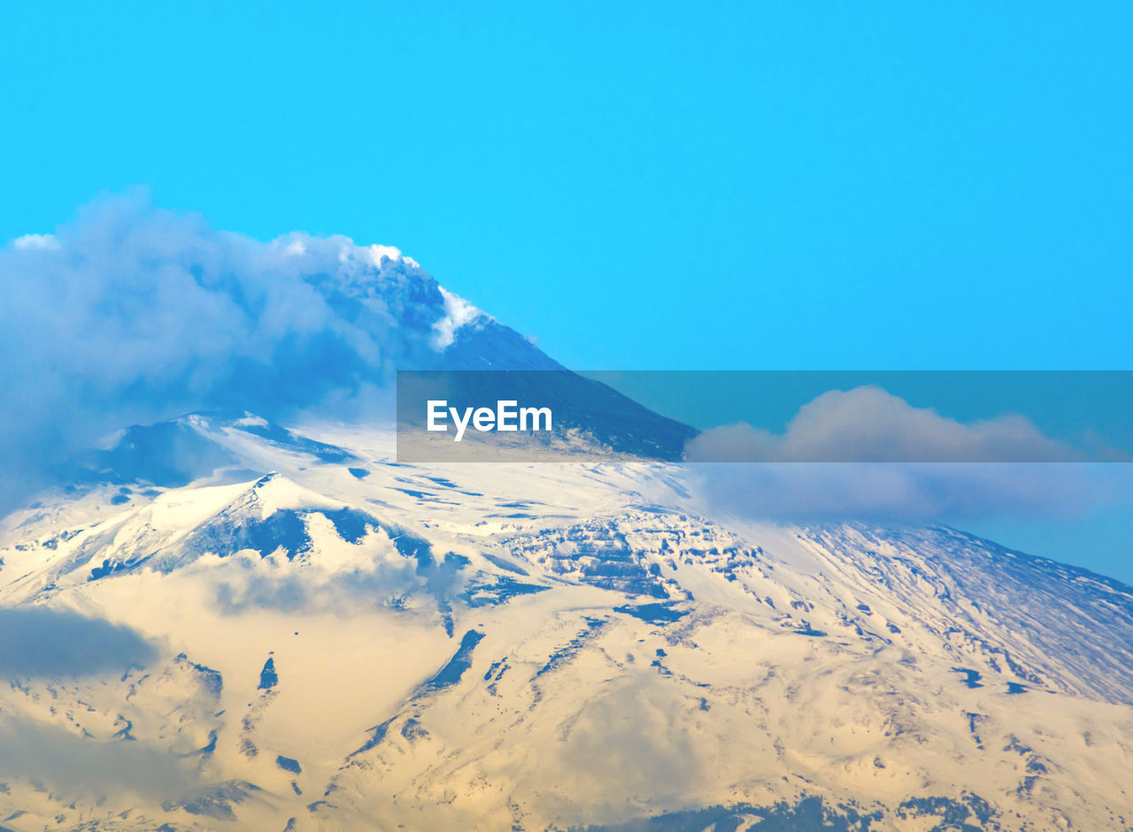 Scenic view of snowcapped mountains against blue sky