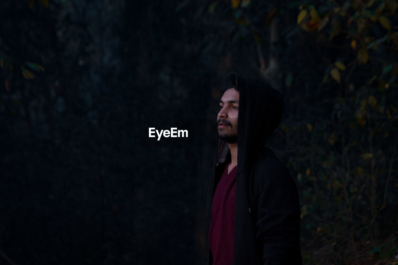 Young man looking away in forest