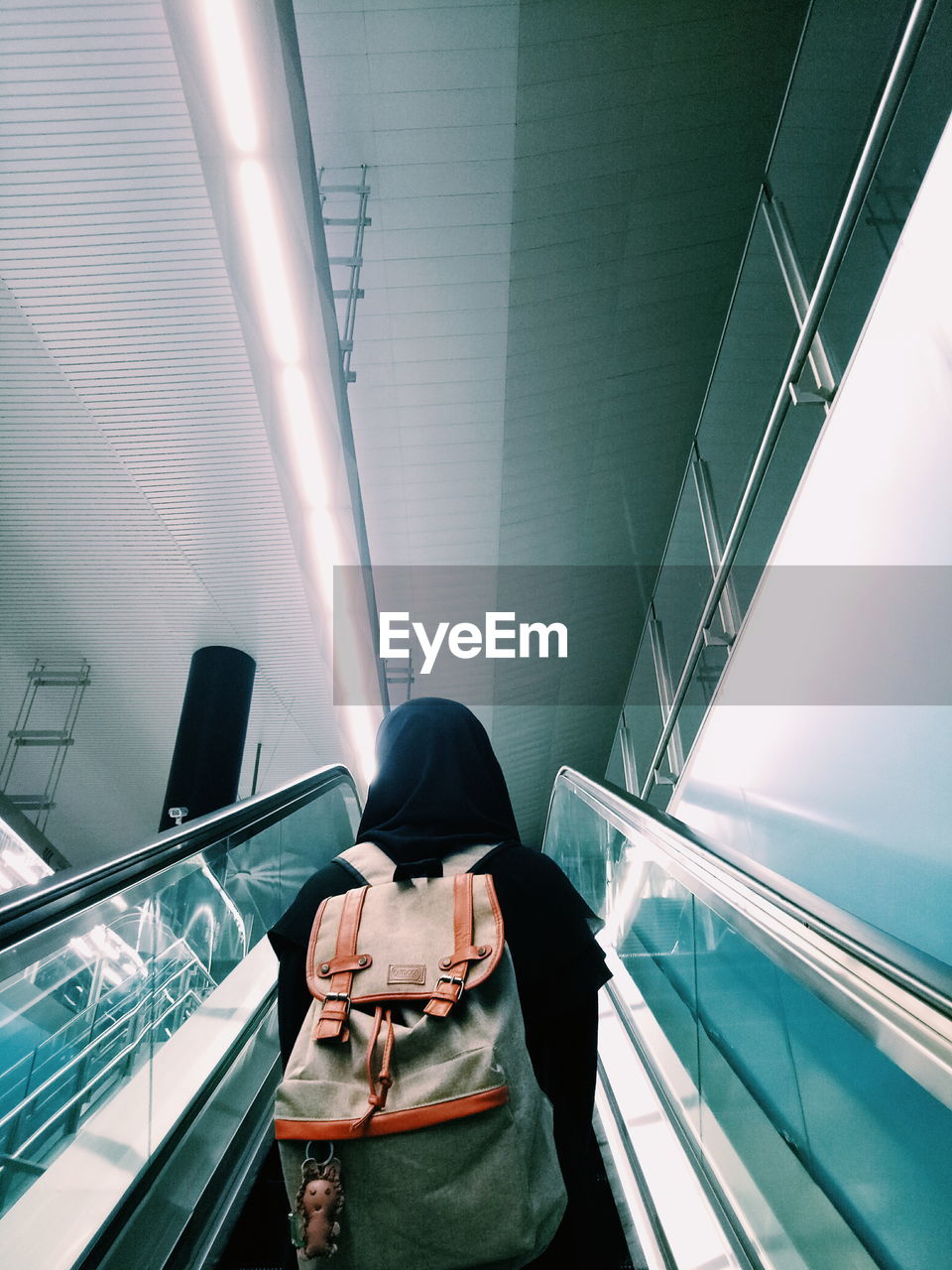 Rear view of woman standing on escalator