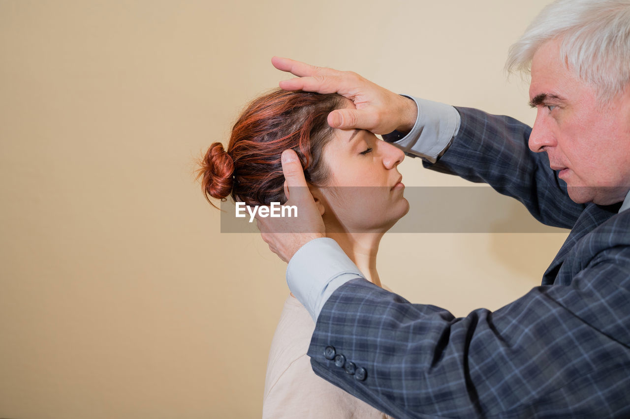 Portrait of man treating female patient against wall