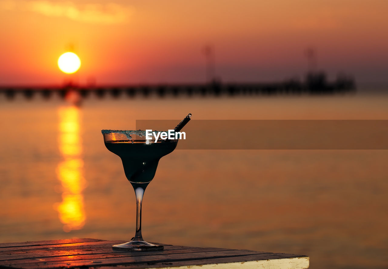 Close-up of drink against seascape at sunset