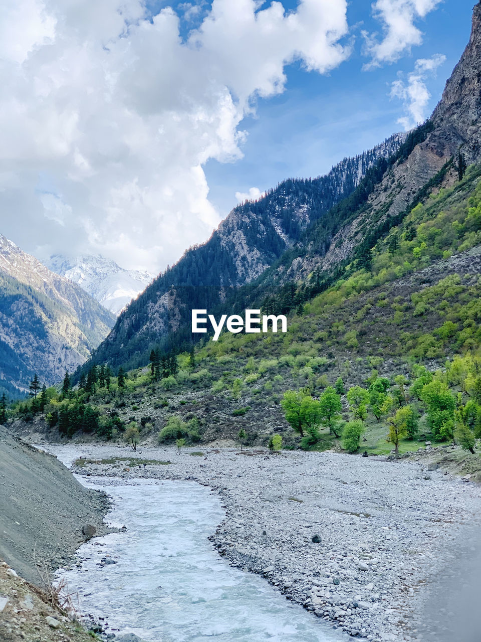 SCENIC VIEW OF RIVER FLOWING BY MOUNTAINS AGAINST SKY