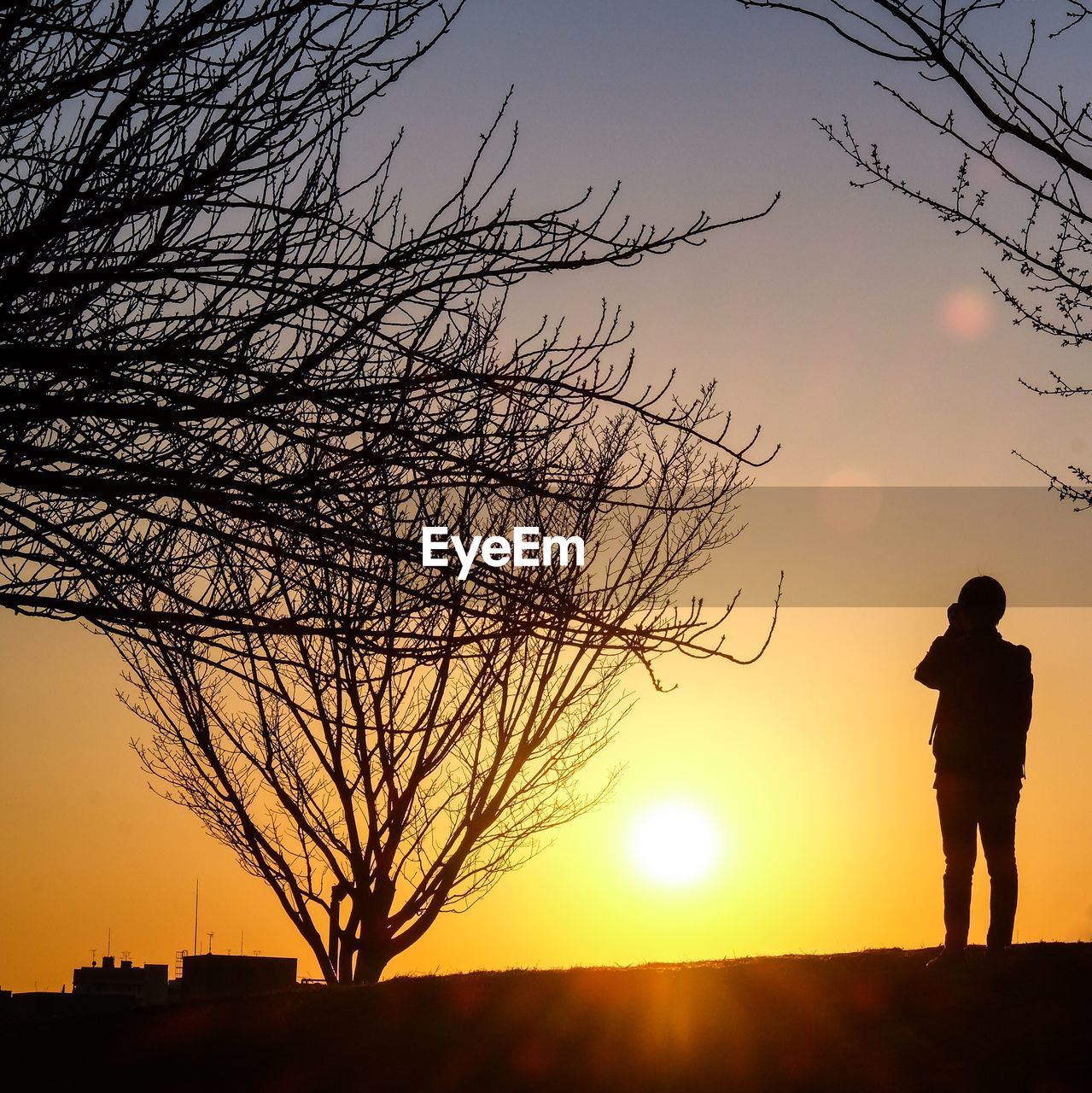 SILHOUETTE MAN STANDING ON FIELD AGAINST SKY AT SUNSET