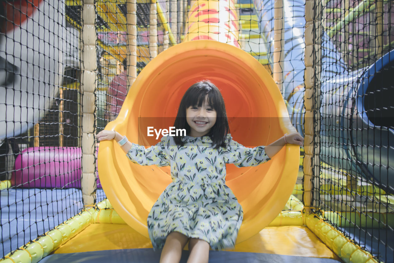 Portrait of smiling innocent girl sitting in slide