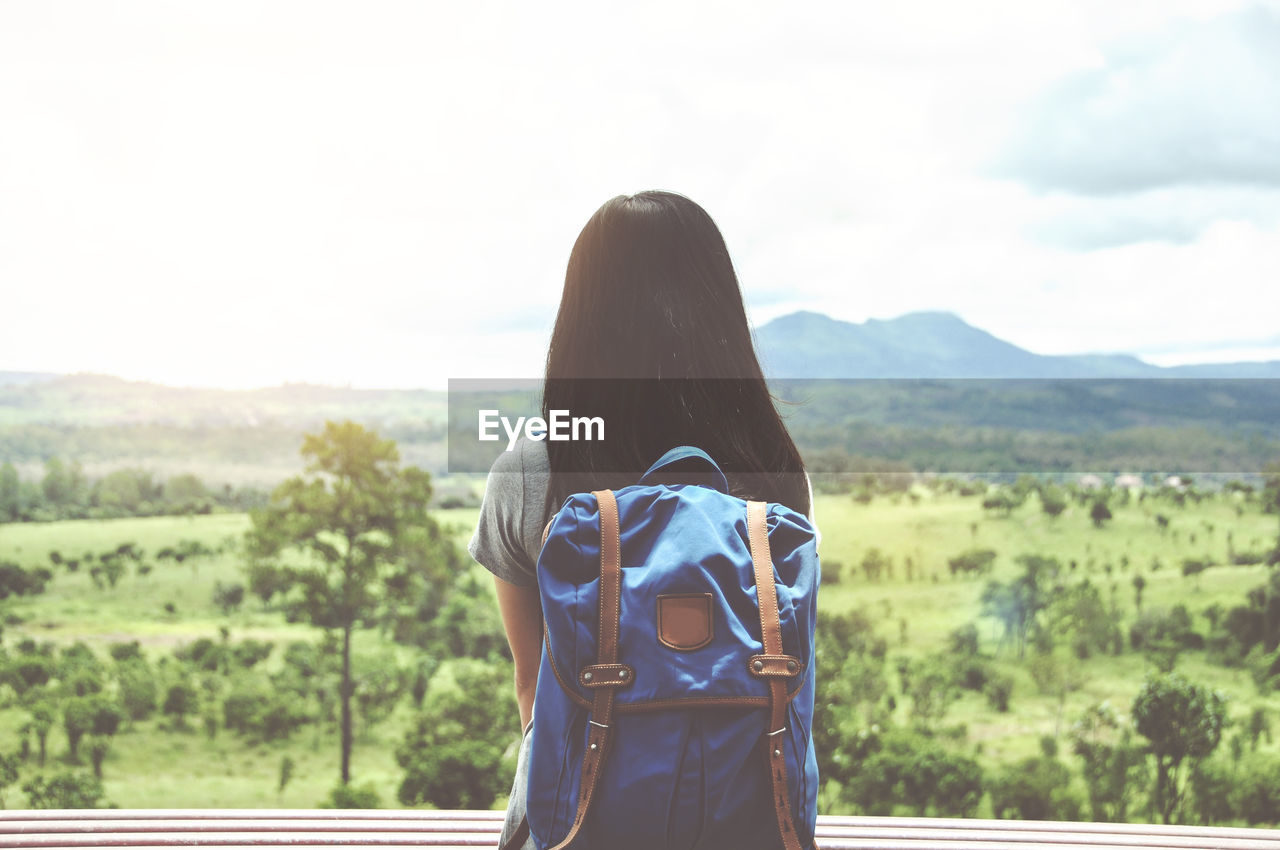 Rear view of woman sitting against landscape