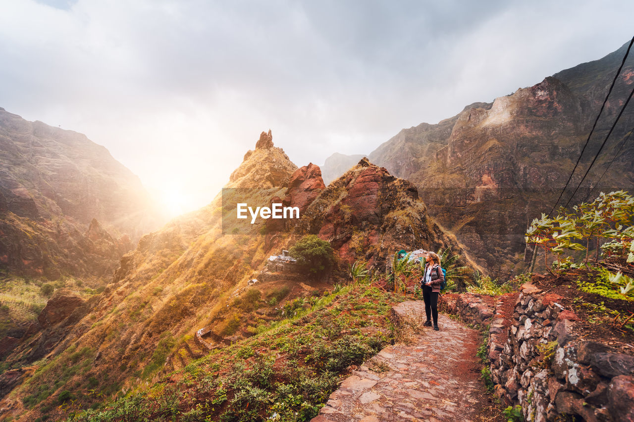 Woman looking at view while standing against mountain during sunrise
