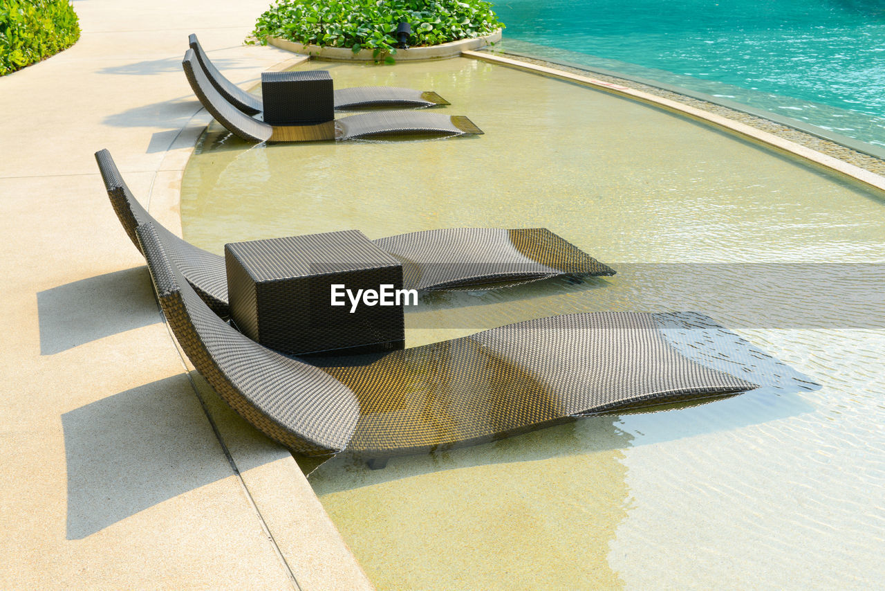HIGH ANGLE VIEW OF CHAIRS AND TABLE AT SWIMMING POOL