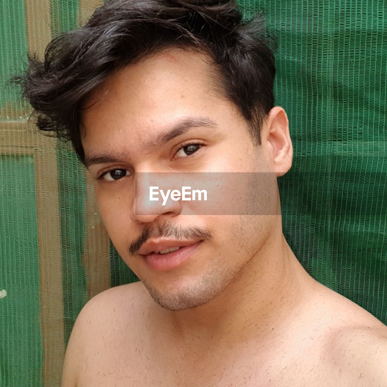 Close-up portrait of shirtless man against fabric