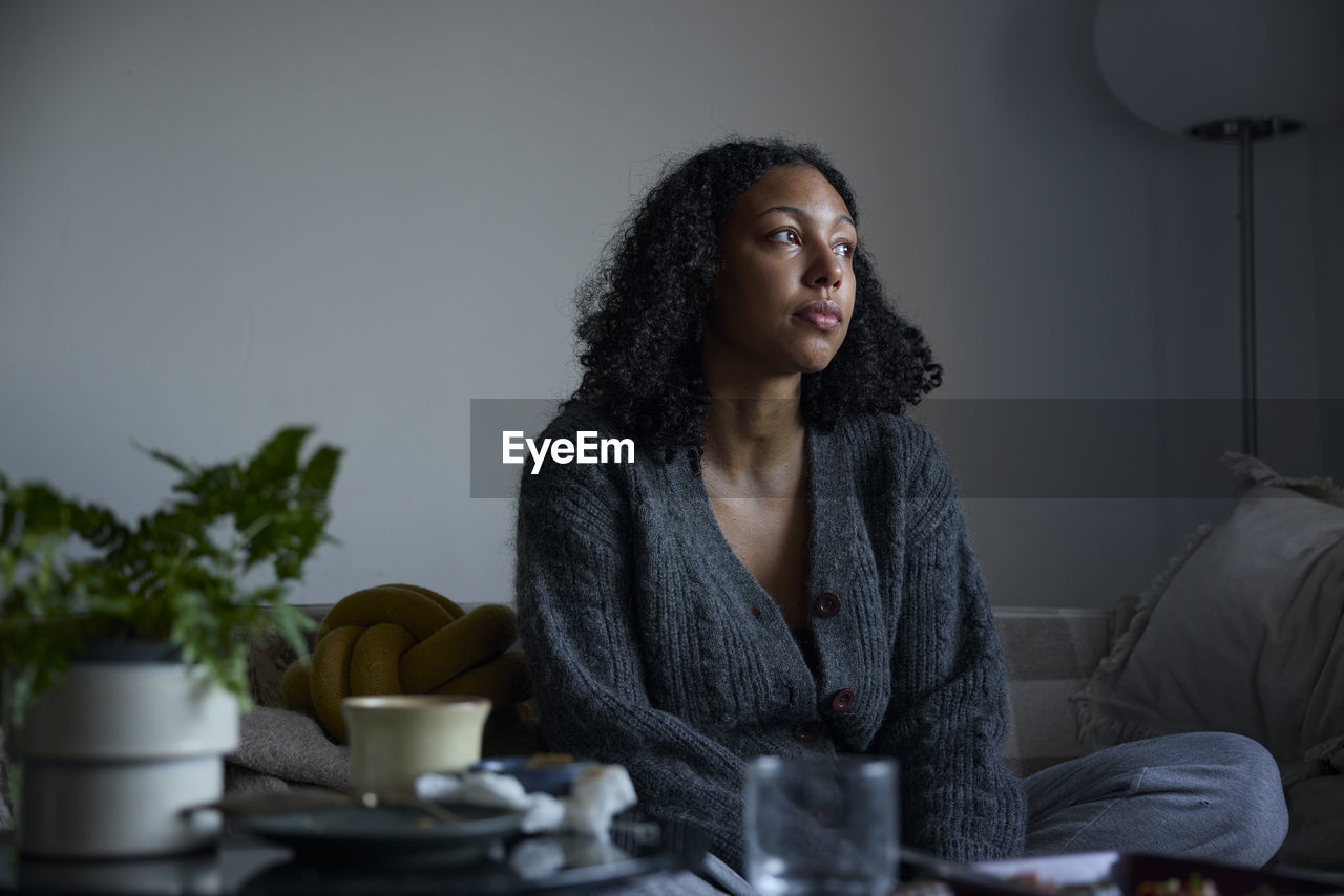 Pensive young woman sitting at home