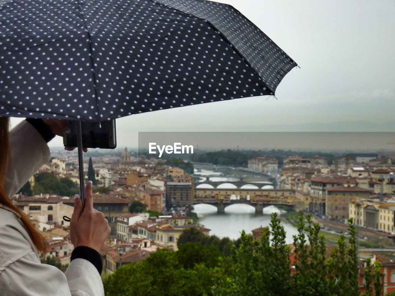 CLOSE-UP OF PERSON PHOTOGRAPHING CITYSCAPE AGAINST SKY