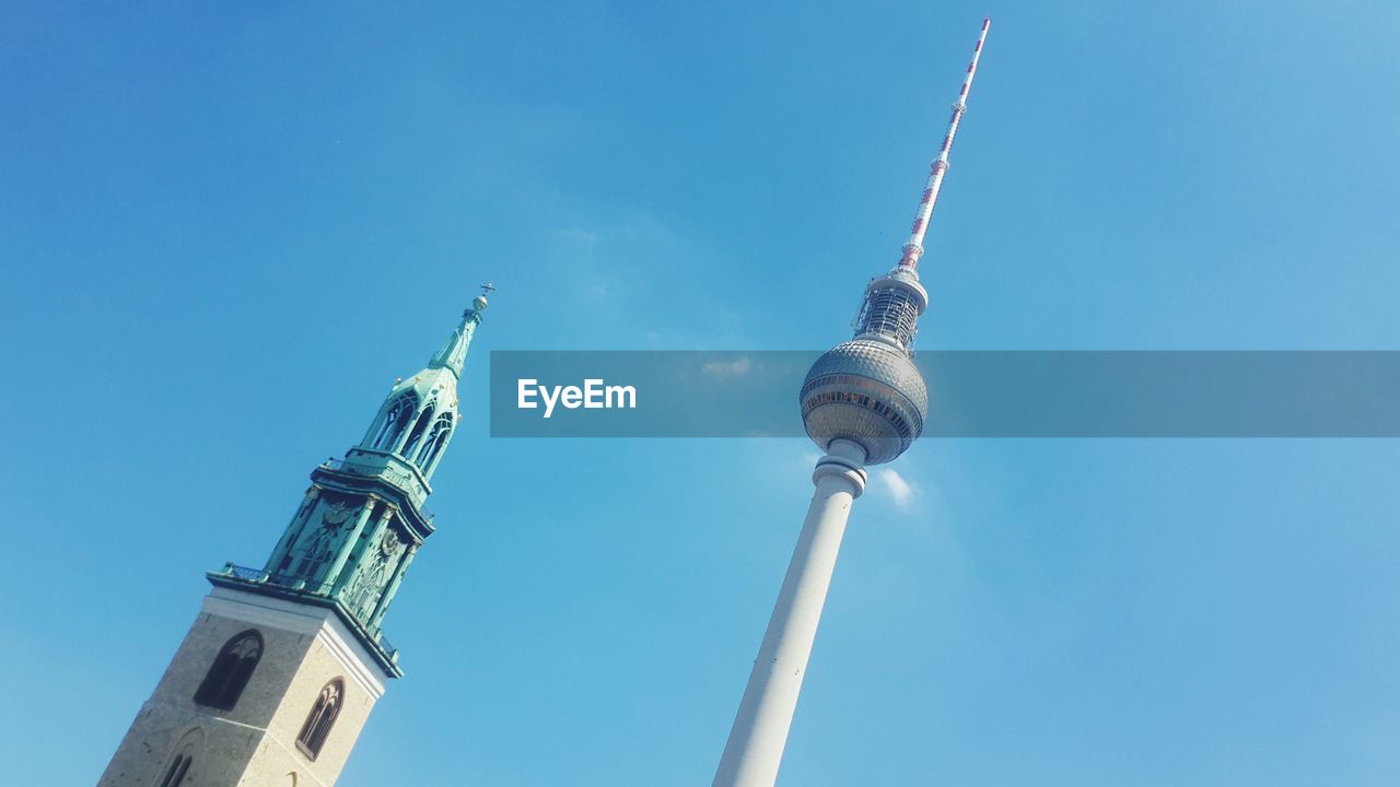 Low angle view of st mary cathedral and fernsehturm against blue sky