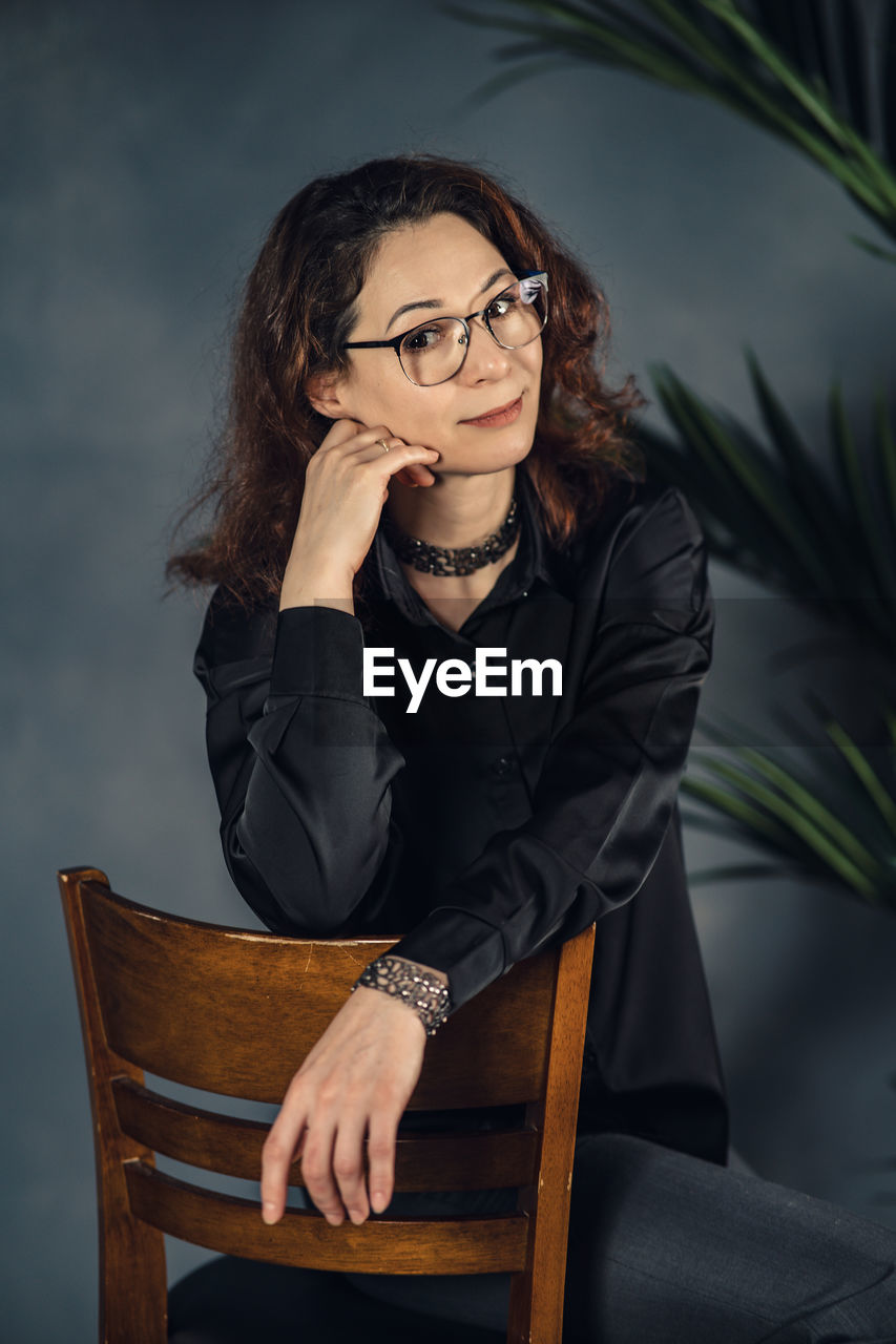 Woman leader in glasses posing in the studio sitting on chair