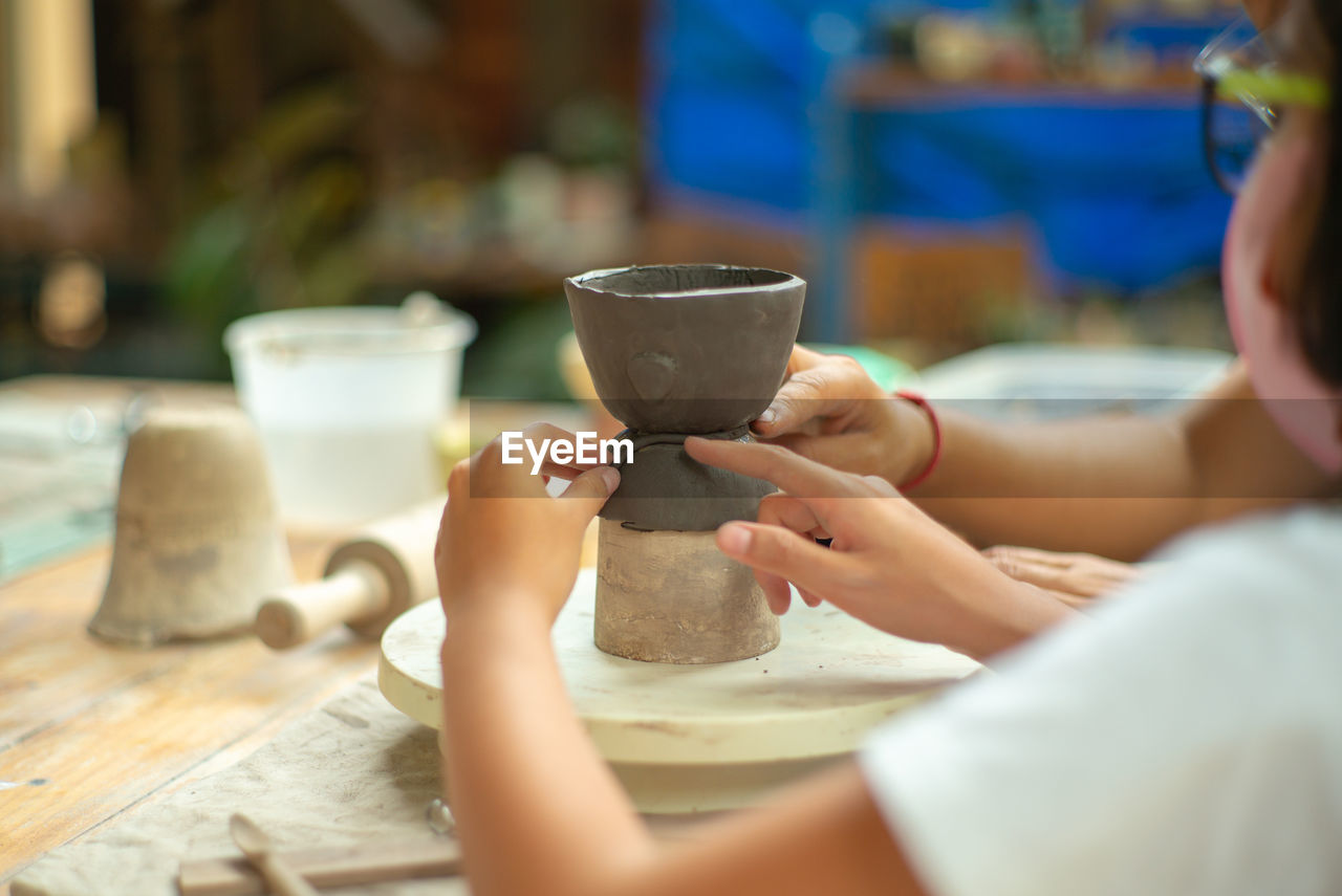 Girl making pot on pottery wheel
