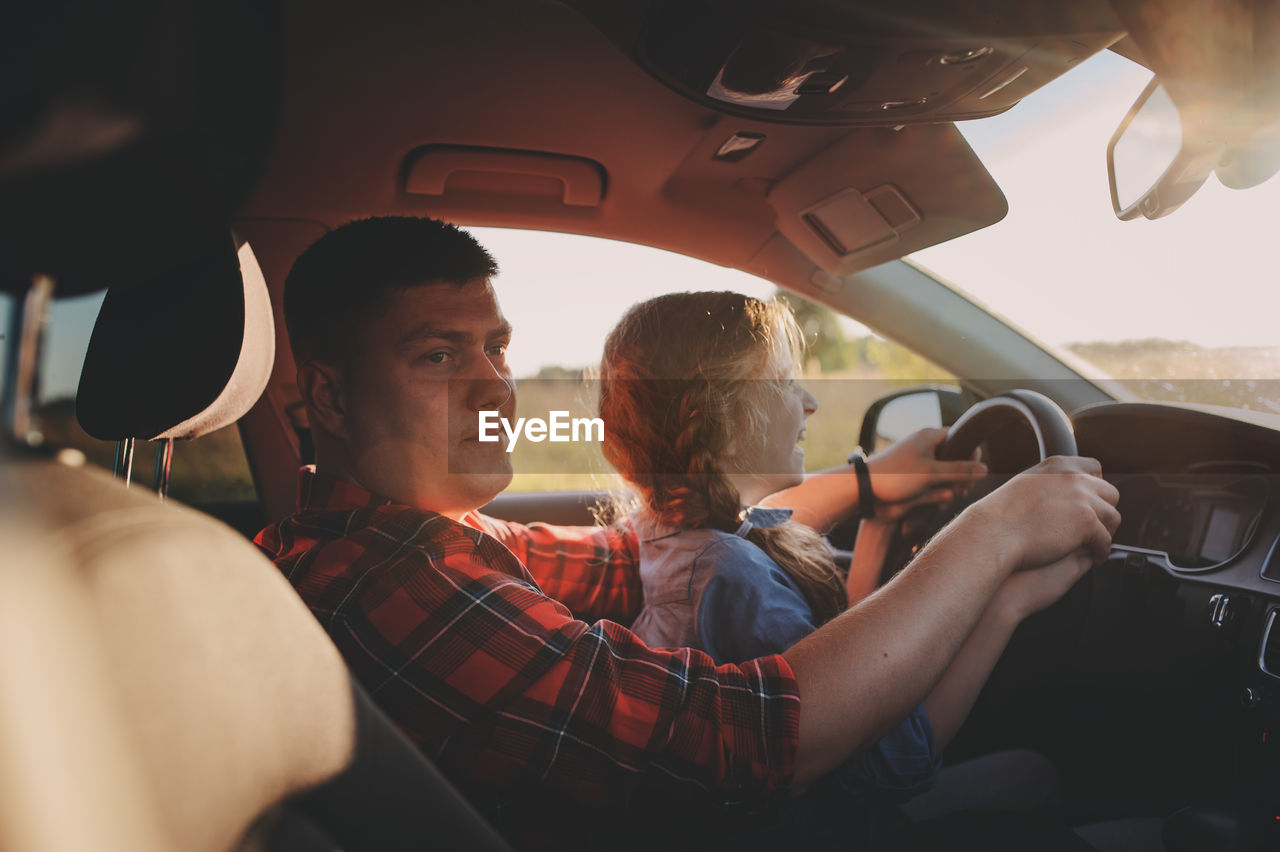 Father teaching driving to daughter in car