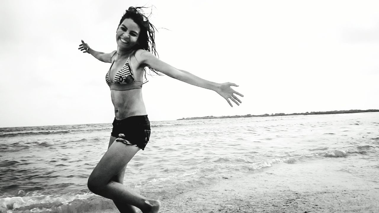 FULL LENGTH PORTRAIT OF YOUNG WOMAN STANDING AT BEACH