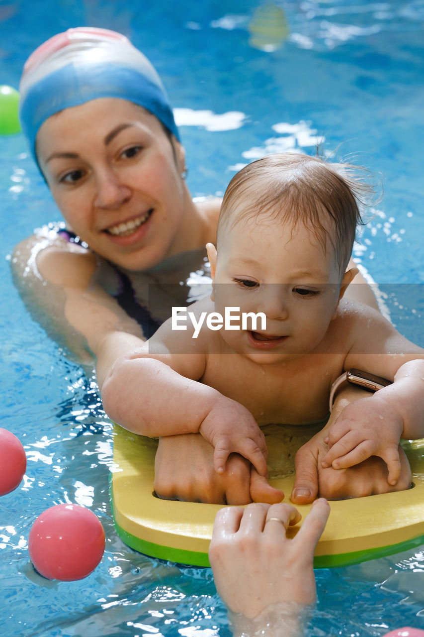 Swimming pool baby boy trained to swim in water healthy and sport family with infant, active parent