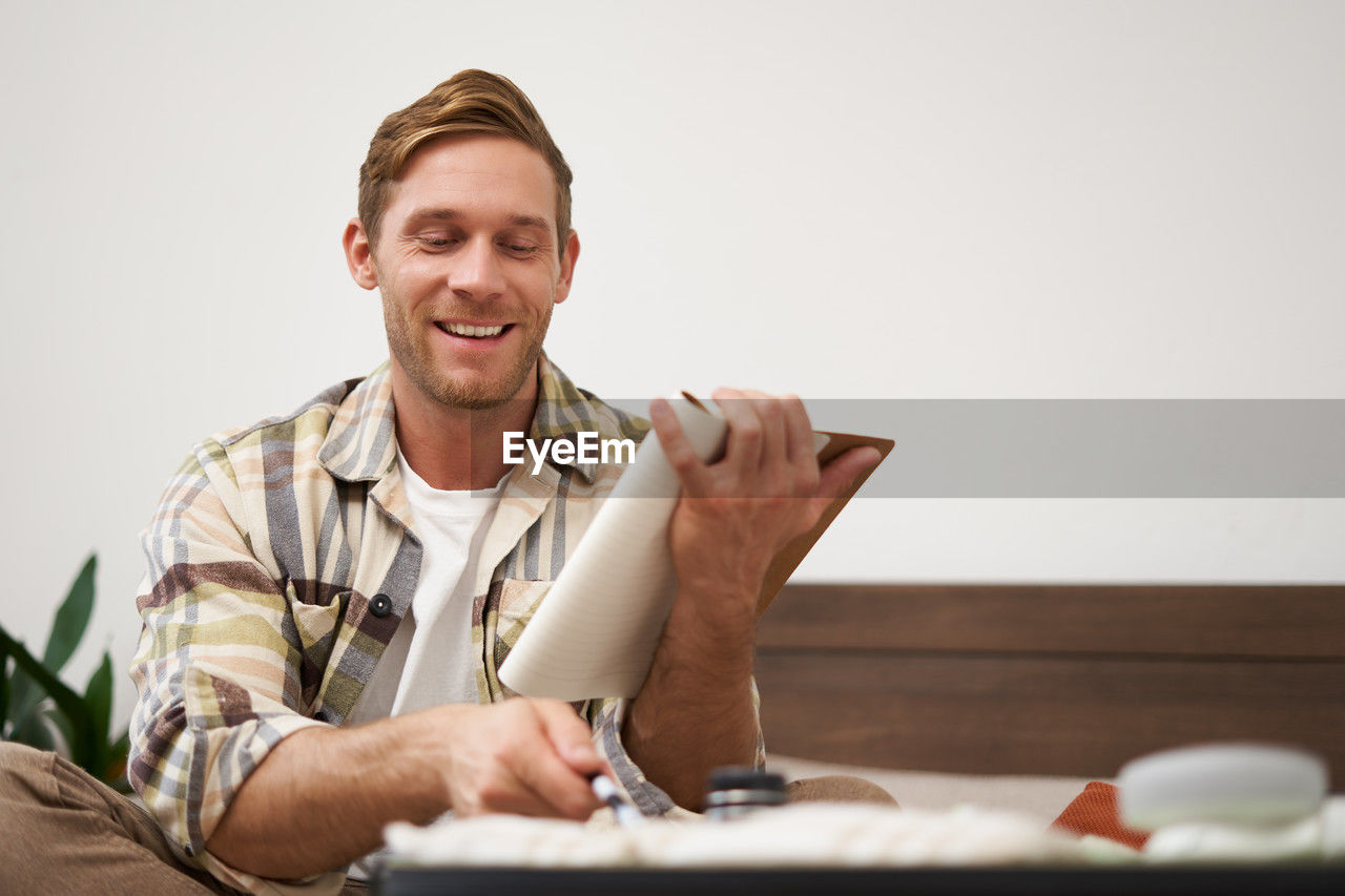 portrait of young man using mobile phone while sitting on table