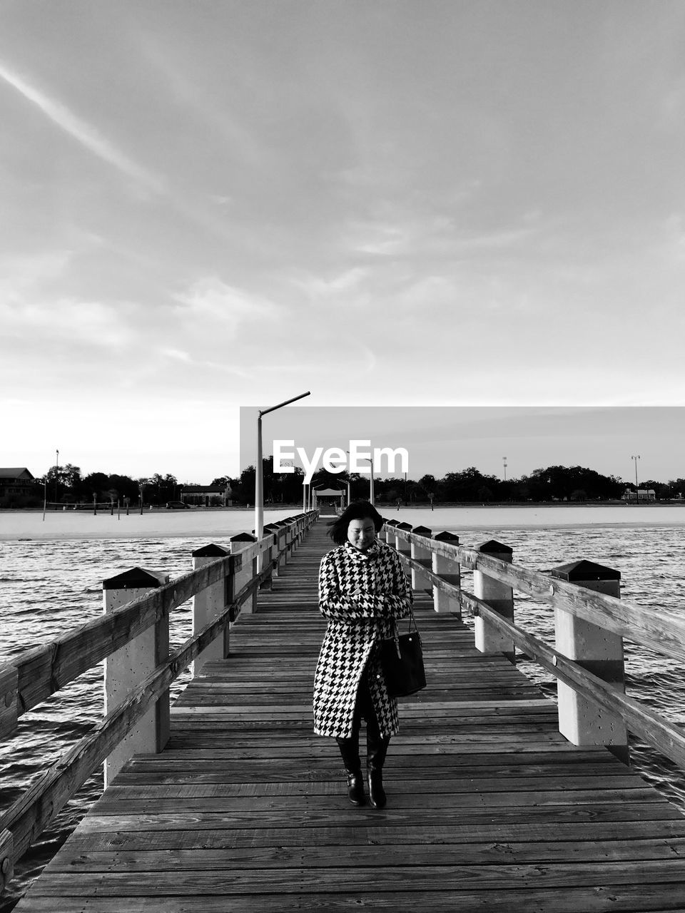 Woman walking on pier over sea against sky
