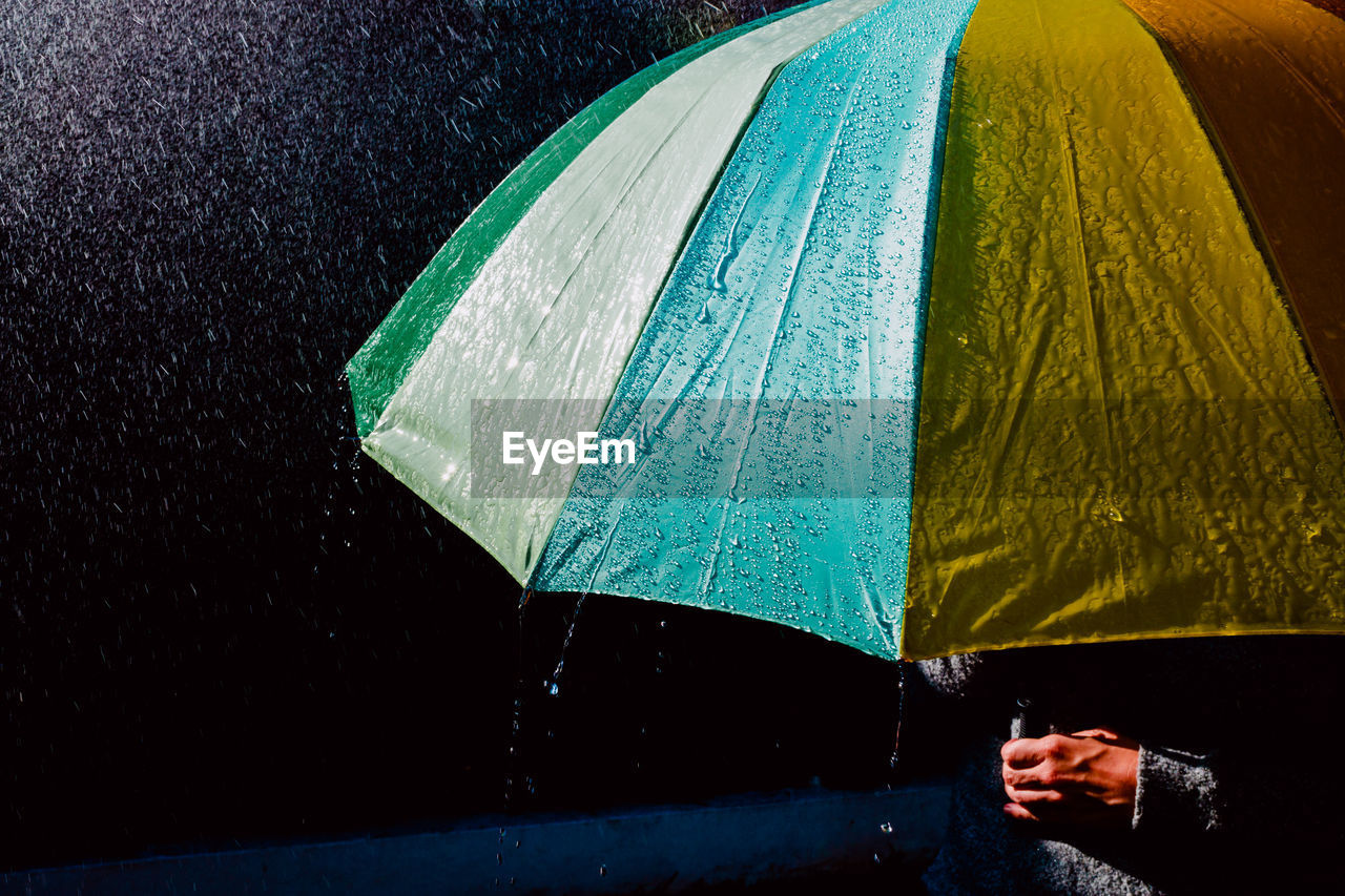 Midsection of person holding umbrella during rain