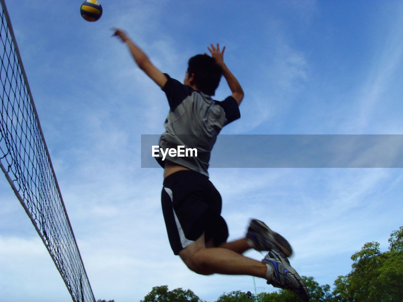 Full length of man playing volleyball against sky