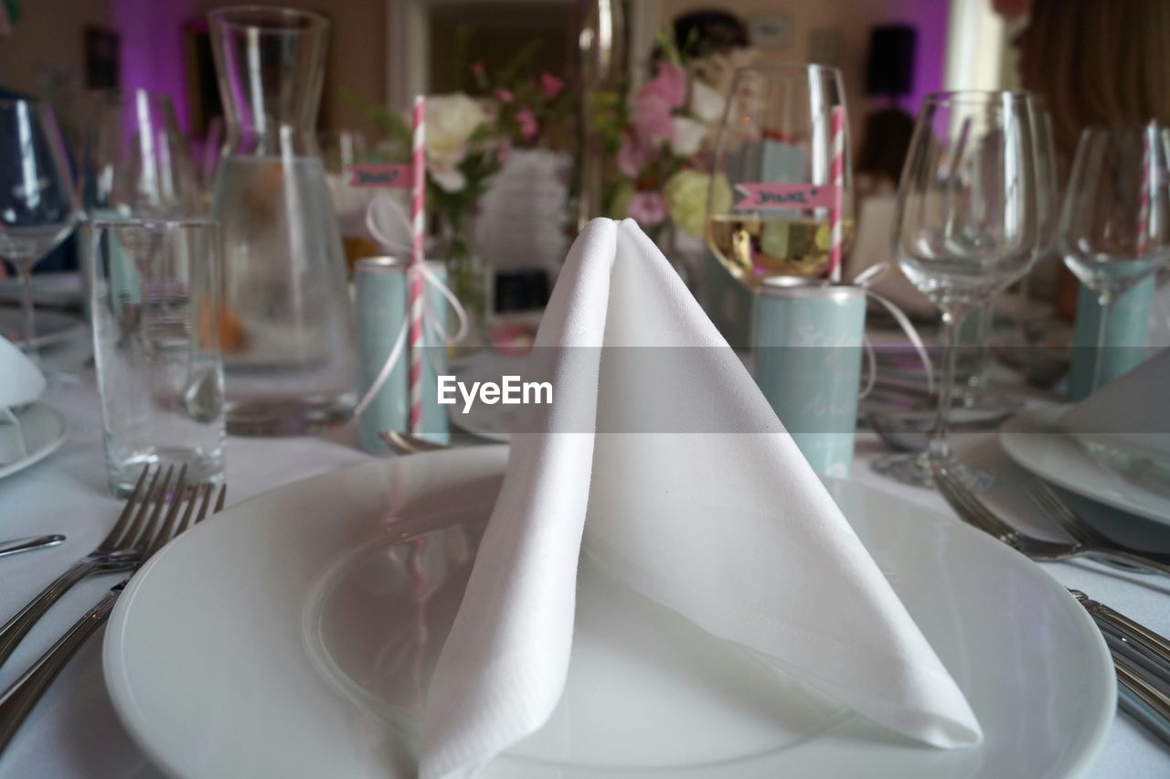 Napkin on plate by wineglasses on table for wedding