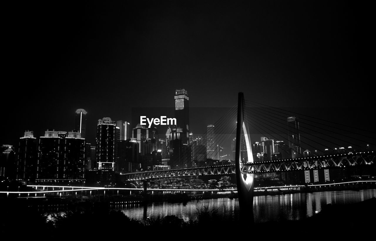 Low angle view of bridge against cityscape at night