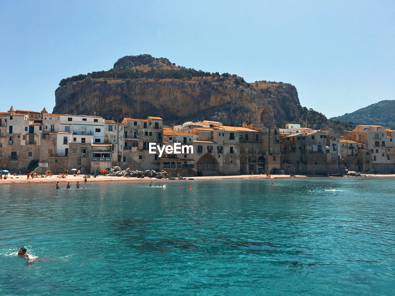 Scenic view of sea and buildings against clear blue sky