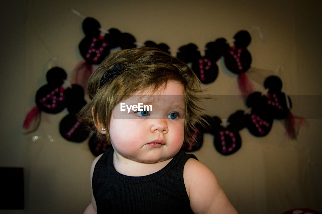 Cute baby girl looking away while sitting at home during birthday party