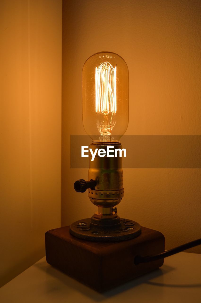 CLOSE-UP OF LIGHT BULB AGAINST YELLOW WALL