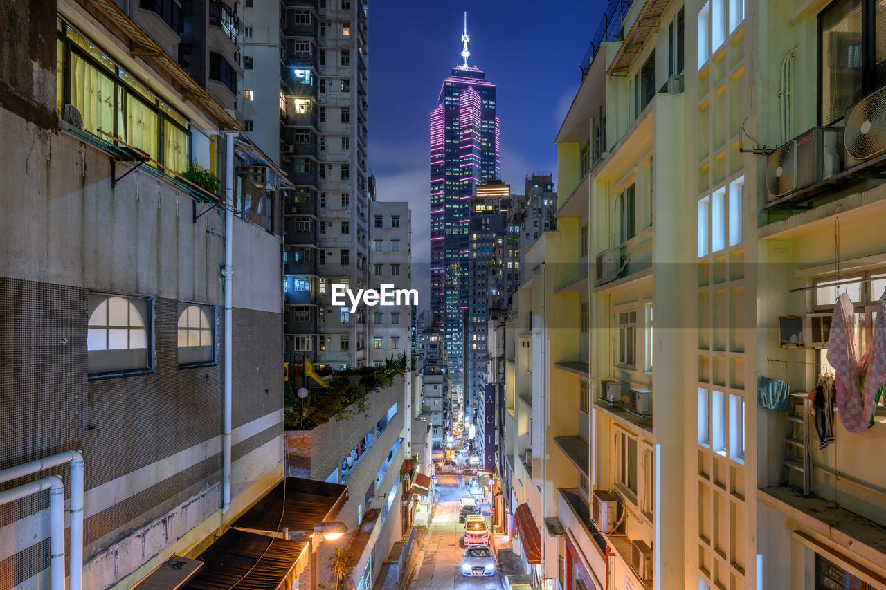 Illuminated street amidst buildings in city at night