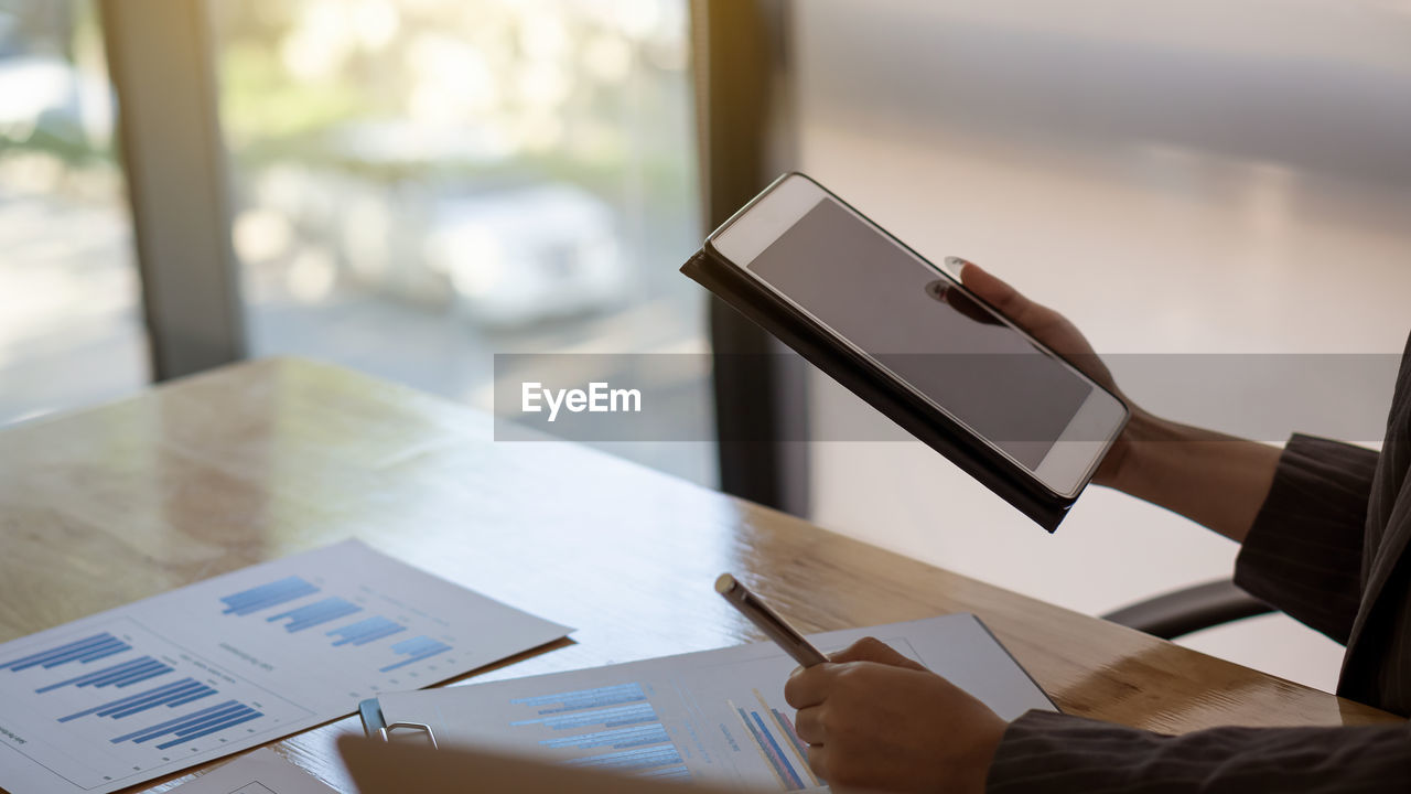 Cropped image of woman using digital tablet at office